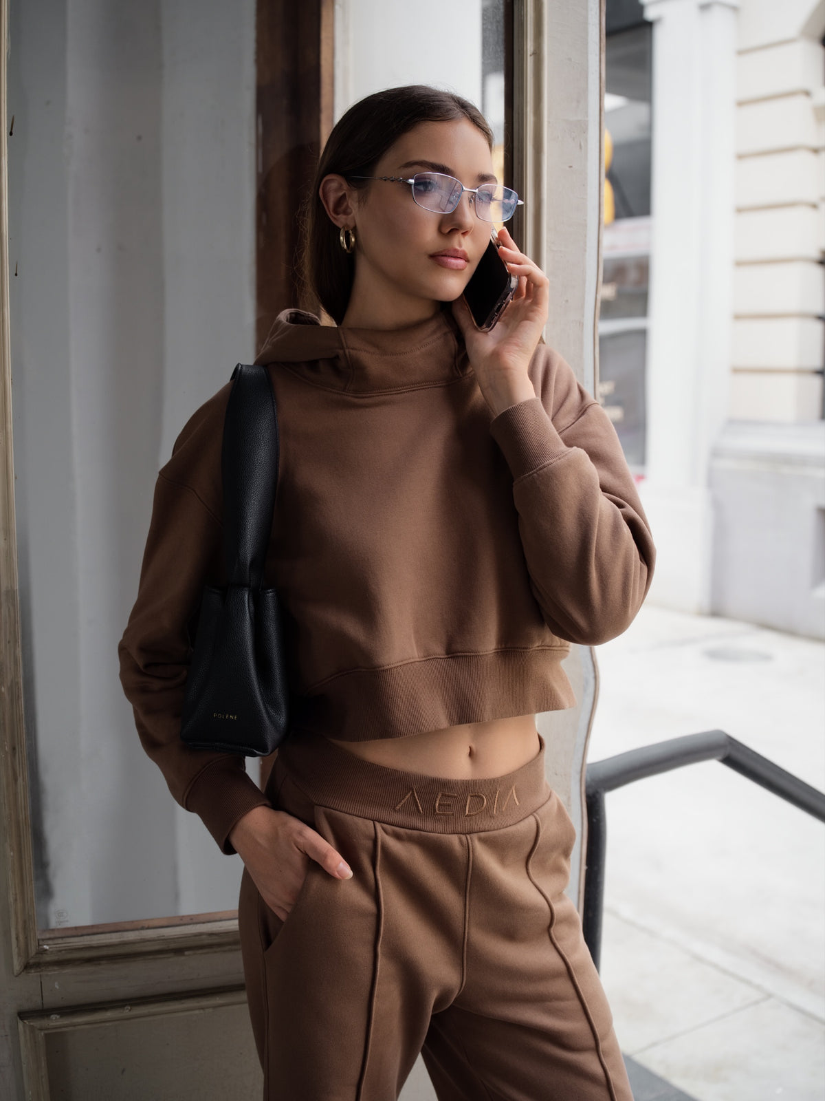 Model wearing the AEDIA Funnel Hoodie in Double Shot by a window