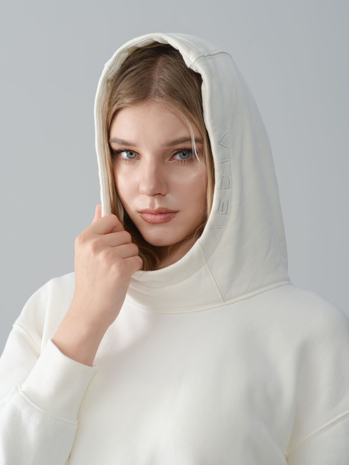 Close-up of the AEDIA Funnel Hoodie hood and tonal logo in Milk